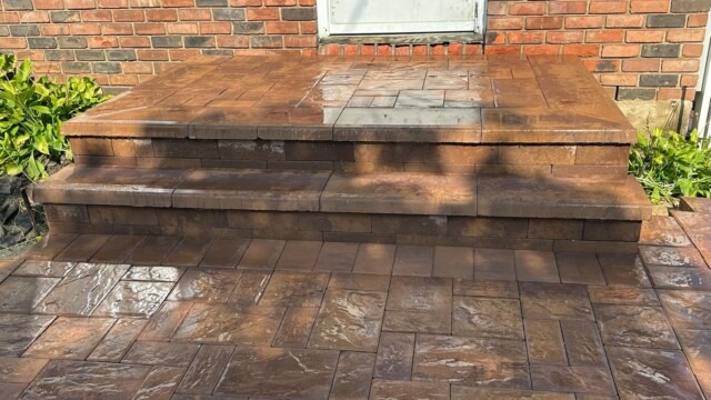 Custom-built paver entrance steps with warm-toned stone perfectly integrated with a brick home exterior, by Constructive Greens