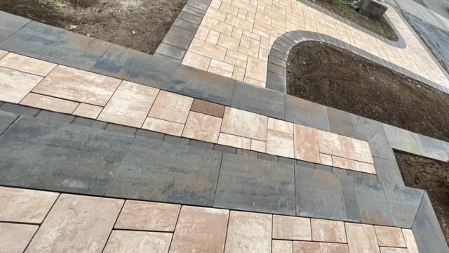 Custom-curved paver walkway with detailed border stone installation by Constructive Greens