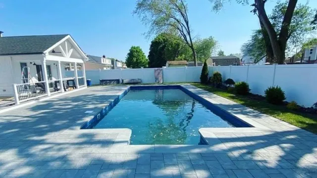 Professional pool deck renovation featuring high-end paver installation surrounding a swimming pool by Constructive Greens